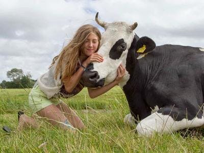 Meisje knuffelt koe in het weiland
